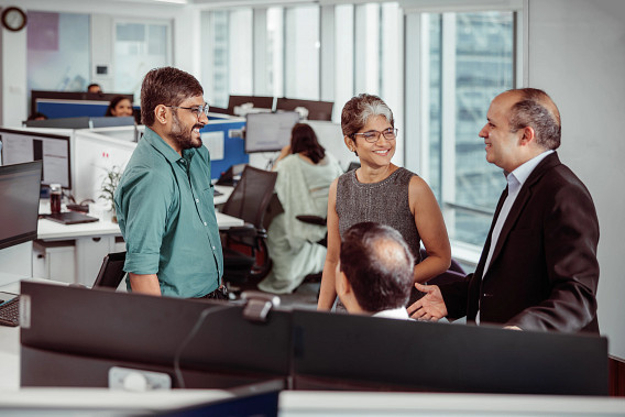 A group of colleagues stood around in an office having a conversation