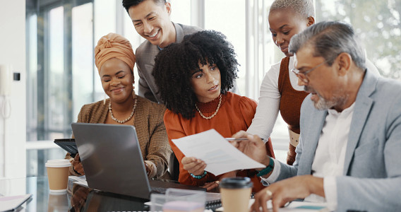 A group of colleagues discussing work around a laptop
