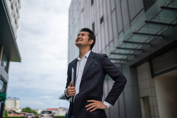 Young businessperson standing in city, looking up towards the buildings